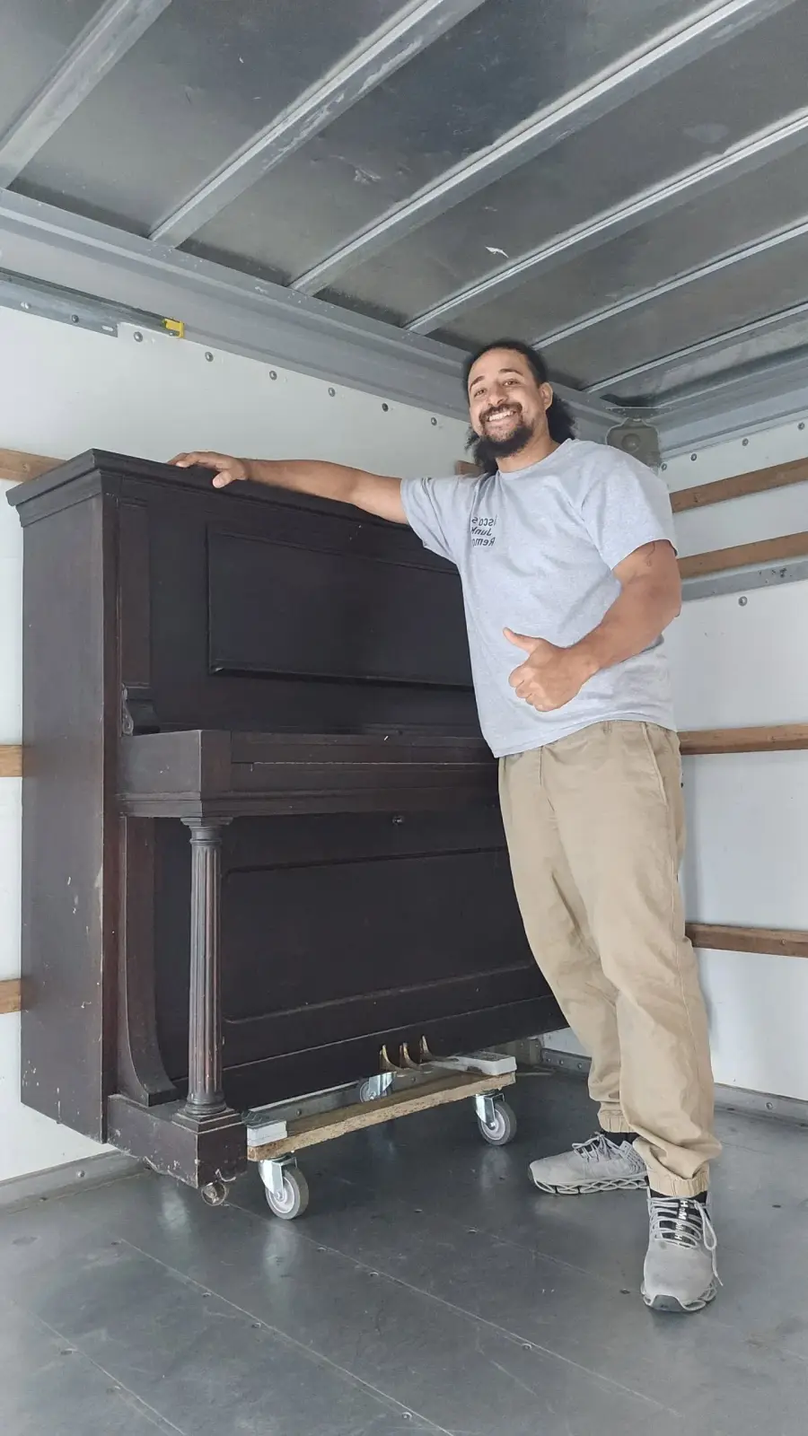 Sisco team member helping move a heavy upright piano